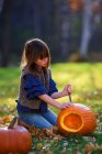 Mädchen schnitzt einen Halloween-Kürbis im Garten, USA — Stockfoto