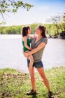 Mère debout près d'un lac portant sa fille — Photo de stock