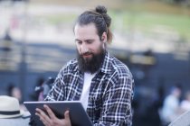 Homem sentado ao ar livre usando um tablet digital — Fotografia de Stock