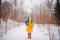 Girl standing in the snow holding a bunch of flowers — Stock Photo