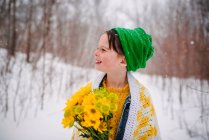 Sorrindo Menina de pé na neve segurando um monte de flores — Fotografia de Stock
