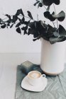 Copo de café ao lado de um vaso e vela — Fotografia de Stock