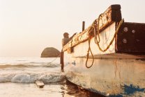 Pescador atando su barco en la playa, Goa, India - foto de stock