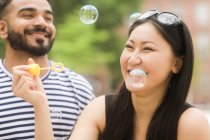 Пара тримає бульбашкову паличку, що дме мильні бульбашки — стокове фото