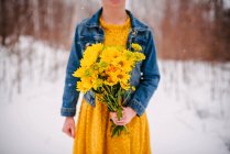 Крупним планом дівчина, що стоїть на снігу, тримає купу квітів — стокове фото