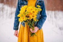 Primo piano di una ragazza in piedi sulla neve con un mazzo di fiori in mano — Foto stock