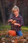 Rapaz sorridente a esculpir uma abóbora de Halloween no jardim, Estados Unidos — Fotografia de Stock