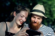 Улыбающаяся пара смотрит на мобильный телефон — стоковое фото