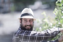Усміхнений чоловік стоїть в саду обрізаючи чагарник — стокове фото