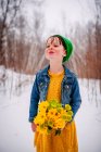Girl standing in the snow holding a bunch of flowers — Stock Photo
