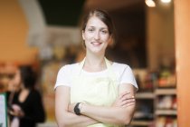 Retrato de una asistente de ventas sonriente con los brazos cruzados - foto de stock