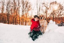 Adorable little boy with his dog on snowy meadow — Stock Photo