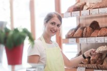 Assistente de vendas sorridente em uma padaria — Fotografia de Stock