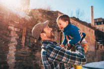 Father standing outside lifting his son in the air — Stock Photo