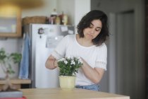 Mulher cuidando de uma planta de panela em sua cozinha — Fotografia de Stock