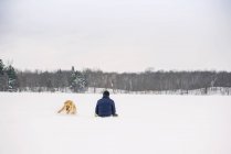 Mann und Hund spielen im Schnee — Stockfoto