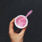 Mão humana segurando uma xícara de sorvete de morango — Fotografia de Stock