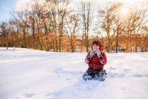 Menino sentado no jardim comendo neve — Fotografia de Stock