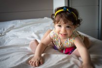 Porträt eines lächelnden Mädchens, das auf einem Bett sitzt — Stockfoto