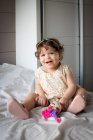 Portrait of a smiling girl sitting on a bed — Stock Photo