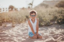 Портрет улыбающегося мальчика, сидящего на пляже, Болгария — стоковое фото