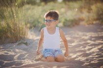 Retrato de un niño sonriente sentado en la playa, Bulgaria - foto de stock