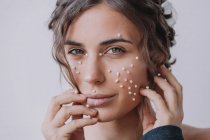 Portrait of a woman with pearls on her face and fingers — Stock Photo