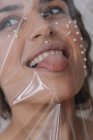 Portrait d'une femme avec des perles sur le visage enveloppé dans du plastique transparent — Photo de stock