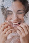 Porträt einer fröhlichen Frau, die sich auf weißem Hintergrund Plastik aus dem Gesicht reißt — Stockfoto