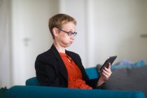 Woman sitting on a couch using a digital tablet and blowing her cheeks — Stock Photo