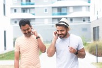 Dos hombres escuchando música en su teléfono móvil - foto de stock