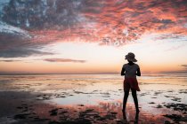 Silhouette eines Mädchens, das bei Sonnenuntergang am Strand steht, Australien — Stockfoto
