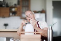 Woman sitting at a table fixing a lamp — Stock Photo