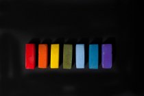 Pastéis de óleo macio multicoloridos em uma linha no fundo preto — Fotografia de Stock