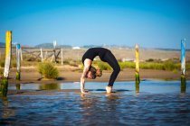 Woman on Los Lances beach doing a wheel yoga pose, Tarifa, Cadiz, Andalusia, Spain — Stock Photo