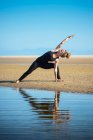 Woman on Los Lances beach doing an extended side angle yoga pose, Tarifa, Cádiz, Andaluzia, Espanha — Fotografia de Stock