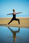 Donna sulla spiaggia di Los Lances facendo posa guerriero II yoga, Tarifa, Cadice, Andalusia, Spagna — Foto stock