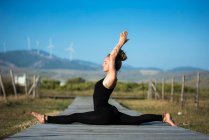 Femme sur la plage de Los Lances faisant face splits pose de yoga, Le parc naturel du détroit, Tarifa, Cadix, Andalousie, Espagne — Photo de stock