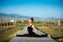 Женщина на пляже Lances делает передние сплит yoga поза, пролив природный парк, tarifa, cadiz, andalusia, Испания — стоковое фото
