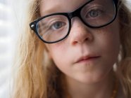 Portrait d'une fille blonde avec des taches de rousseur portant des lunettes — Photo de stock