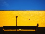 Vista panorámica de la pared amarilla con sombras contra un cielo azul, Australia - foto de stock