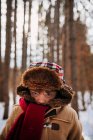 Portrait d'un garçon dans les bois portant un chapeau d'hiver et un manteau chaud — Photo de stock