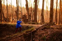 Junge läuft auf einem umgestürzten Baum im Wald, USA — Stockfoto