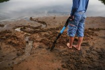 Мальчик, стоящий на пляже с лопатой в руках — стоковое фото