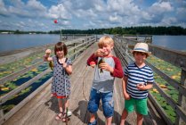 Tres niños que pescan en un muelle en el verano, Estados Unidos - foto de stock