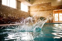 Water splashing in a swimming pool after a person jumps in — Stock Photo