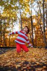 Menino pulando em um trampolim coberto em folhas de outono, Estados Unidos — Fotografia de Stock