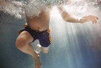 Крупный план мальчика, плавающего под водой в бассейне — стоковое фото