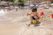Ragazzo che riempie un secchio di sabbia sulla spiaggia, Grecia — Foto stock