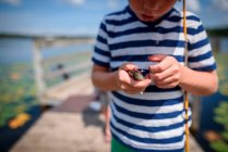 Boy standing on a dock holding a fresh catch of fish, United States — Stock Photo